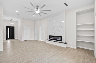 Unfurnished living room with a fireplace, ceiling fan, light hardwood / wood-style flooring, and built in features