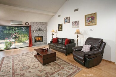 Spacious family room with high beamed ceilings, dramatic raised hearth stone fireplace with mantle, backyard access through the sliding glass doors and modern wood flooring.