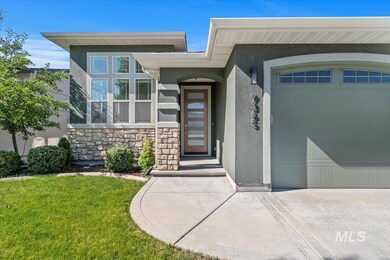 Entrance to property featuring stucco siding, stone siding, a garage, a yard, and driveway