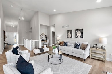 Living area featuring light wood-type flooring, high vaulted ceiling, a chandelier, and recessed lighting