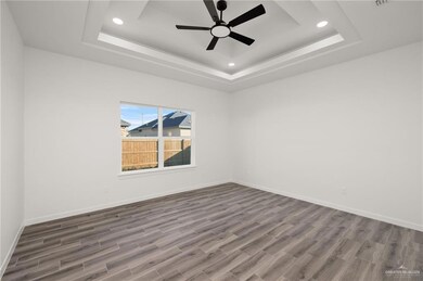 Empty room with a raised ceiling, recessed lighting, dark wood-style flooring, and ceiling fan