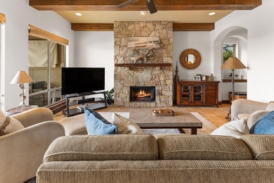 Living room featuring beamed ceiling, a ceiling f