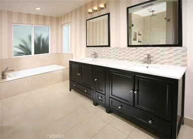 Sumptuous en suite master bathroom with state-of-the-art deep ebony vanity with His and Her dual basin sinks, custom tiled back-splash, dual framed dressing mirrors, recessed and designer lighting, tiled soaking tub, oversized frameless glass enclose