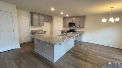 Kitchen featuring recessed lighting, a breakfast bar area, light stone countertops, dark wood-style floors, and gray cabinetry