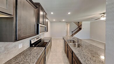 Kitchen featuring tasteful backsplash, stainless steel appliances, sink, light stone countertops, and ceiling fan