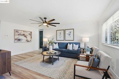 Living room with light wood-type flooring, a ceiling fan, and ornamental molding