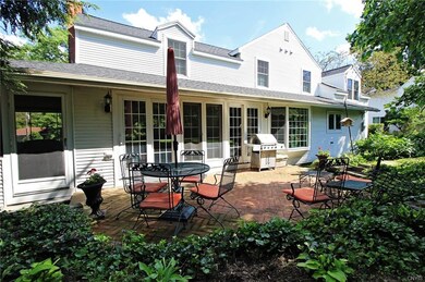 LOVELY BRICK PATIO SURROUNDED BY SHRUBS AND TREES 