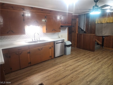 Kitchen with light countertops, light wood-style flooring, tasteful backsplash, and stainless steel dishwasher