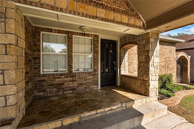 Doorway to property featuring a porch and brick and stone siding
