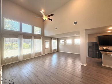 Unfurnished living room with a towering ceiling, dark wood-type flooring, and ceiling fan