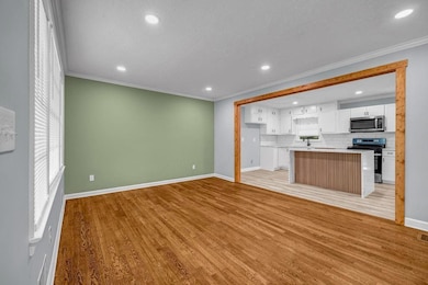 Unfurnished living room with crown molding, recessed lighting, light wood-style floors, and baseboards