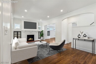 Living room with a healthy amount of sunlight, dark hardwood flooring, crown molding, and a brick fireplace