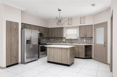 Kitchen with stainless steel appliances, a kitchen island, visible vents, light countertops, and modern cabinets