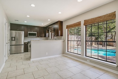 Kitchen with dark brown cabinetry, stainless steel appliances, recessed lighting, backsplash, and a peninsula