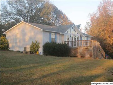 Left side of home shows large front deck, depth of