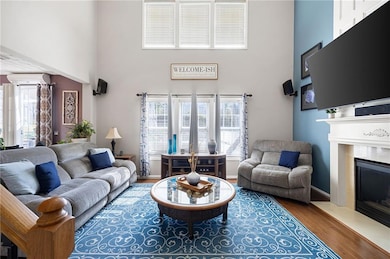 Living area featuring a high ceiling, wood finished floors, a fireplace, and healthy amount of natural light
