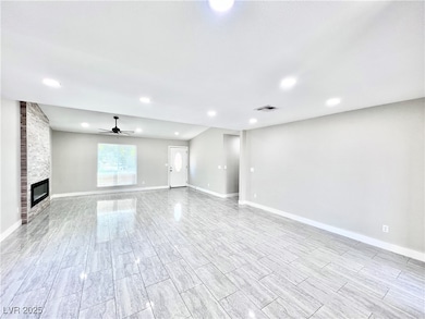 Unfurnished living room featuring a ceiling fan, a fireplace, recessed lighting, and wood finish floors