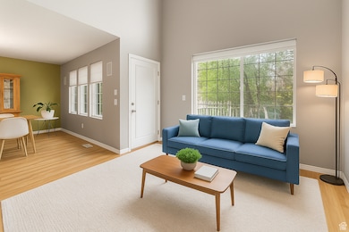 Living area featuring light wood-style floors opens up to the backyard and the dining room