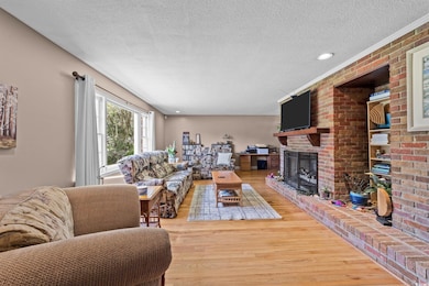 Living area featuring a textured ceiling, a fireplace, wood finished floors, and recessed lighting