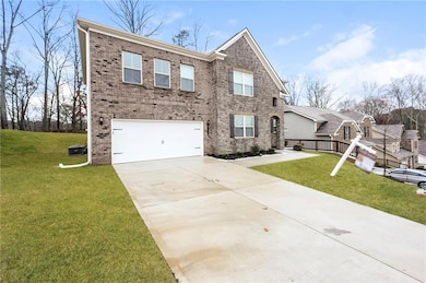View of front of property featuring brick siding, an attached garage, driveway, and a front lawn