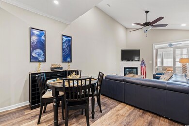 Dining area with a ceiling fan, lofted ceiling, baseboards, light wood-style flooring, and a fireplace
