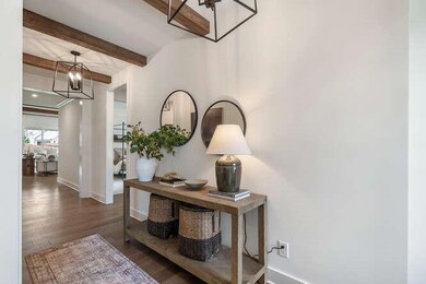 Hallway with beamed ceiling, baseboards, an inviting chandelier, and wood finished floors