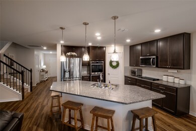 Kitchen featuring 36 inch cabinets, a breakfast bar area, dark wood-style flooring, recessed lighting, and appliances with stainless steel finishes