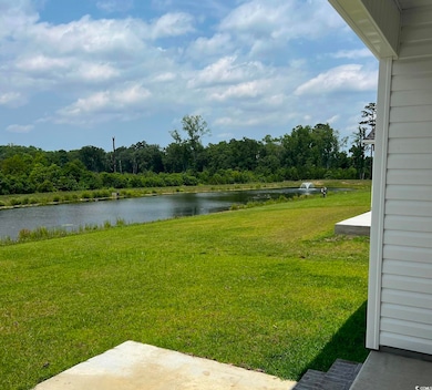 View of grassy yard featuring a water view and a patio area