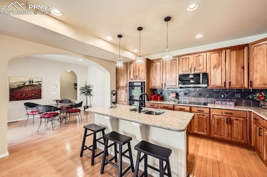 Kitchen with a sink, black appliances, arched walk