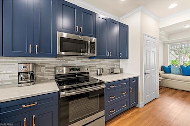 Kitchen with crown molding, blue cabinets, stainle