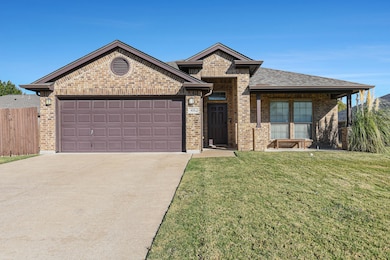 View of front facade featuring concrete driveway, a garage, brick siding, and a porch