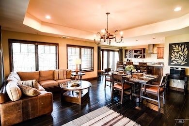 Living area featuring a tray ceiling, dark wood finished floors, recessed lighting, and a chandelier