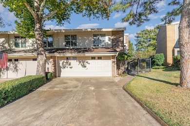 Traditional-style house with concrete driveway, an attached garage, brick siding, and a gate