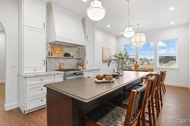 Kitchen with a breakfast bar area, tasteful backsplash, white cabinets, premium range hood, and dark wood-style flooring