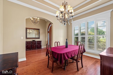 Dining room with a chandelier, arched walkways, wood finished floors, and ornamental molding
