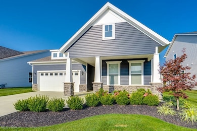 View of front of home with stone siding, covered porch, concrete driveway, and a garage
