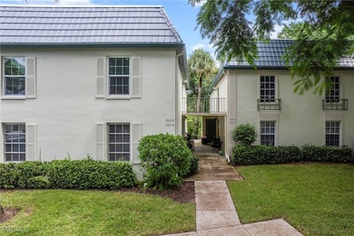 View of front facade featuring a front lawn, stucco siding, and a balcony
