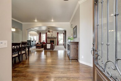 Foyer with dark wood-type flooring, baseboards, ceiling fan, a fireplace, and arched walkways