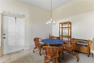 Carpeted dining space featuring a chandelier and baseboards