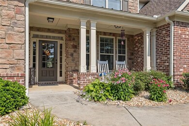 Doorway to property with a porch, brick siding, and roof with shingles