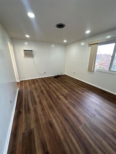 Bedroom featuring dark wood-style floors, recessed lighting, and an AC wall unit