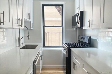 Kitchen featuring stainless steel appliances, decorative backsplash, white cabinets, and light wood-style flooring