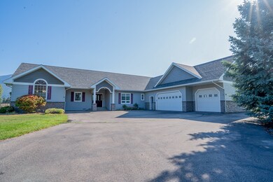 Ranch-style home featuring stone siding, a shingled roof, driveway and attached garage