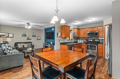 Kitchen with hanging light fixtures, light hardwood / wood-style flooring, ceiling fan with notable chandelier, and stainless steel appliances