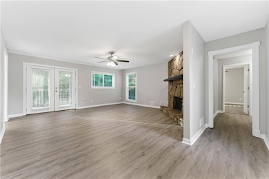 Unfurnished living room with light wood-type flooring, a fireplace, french doors, and ceiling fan