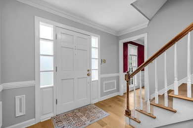 Foyer entrance with light wood-type flooring, stairway, crown molding, and wainscoting