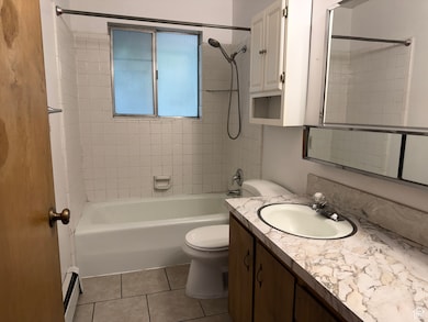 Bathroom featuring shower / washtub combination, vanity, light tile patterned floors, and a baseboard heating unit