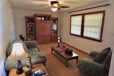 Carpeted living room with a ceiling fan and baseboards