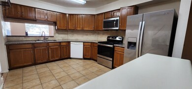 Spacious kitchen area with wooden cabinetry, grani