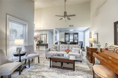 Living area with a towering ceiling, wood finished floors, and a ceiling fan